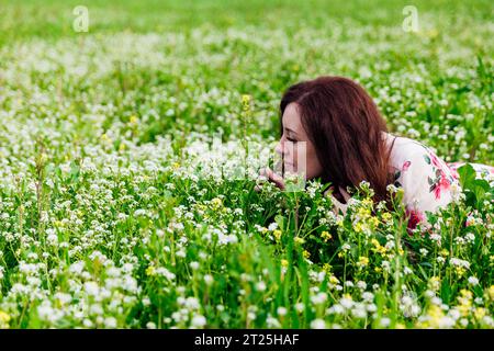 a woman smells flowers in a green clearing Stock Photo