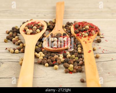 different kinds of dry pepper in spoons on wooden table Stock Photo