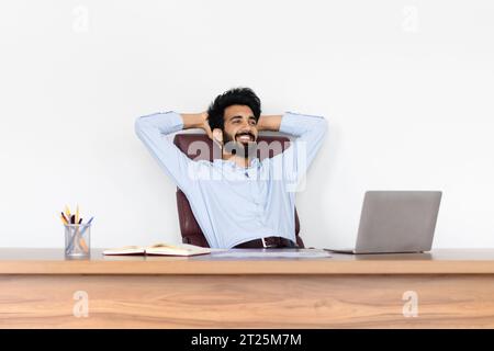 Indian young businessman enjoying his business success, office interior Stock Photo