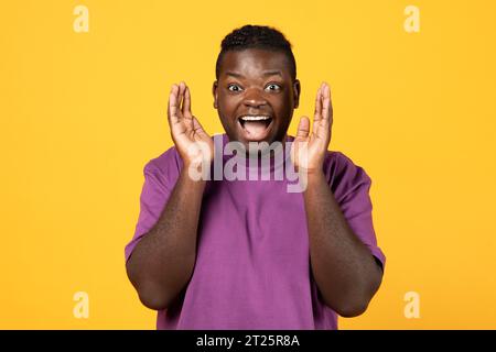 Emotional african american man shouting in excitement on yellow background Stock Photo