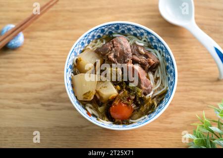 Beef noodle soup. Taiwanese famous food with sliced red braised beef and vegetables in a bowl on wooden table background. Stock Photo