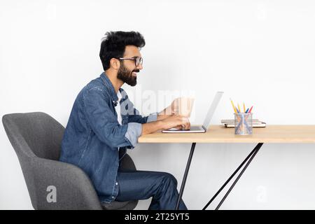 Focused Indian Freelancer Using Laptop at Table Stock Photo