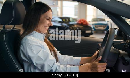 Happy Caucasian successful businesswoman joyful woman sit in new car in automobile shop rent service dealership decide choose renting buying auto Stock Photo