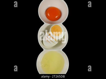 Separated egg yolk from white and boiled egg in bowl isolated on black background Stock Photo