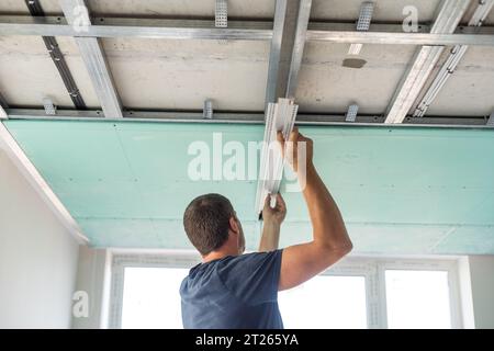 Man assembles profile metal frame for plasterboard ceilings Stock Photo