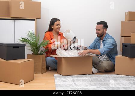 Cheerful couple unpacks moving boxes, dream home. glow of new beginning, joy in the simple moments Stock Photo