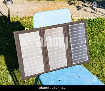 Charging a portable solar battery from the sun at a summer camping site. Clean energy for camp use. Stock Photo