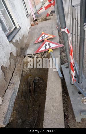 Construction site with repair drain of an old house with warning signs lying on the ground Stock Photo