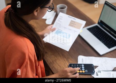 At home, a woman utility bills online payment receipts in hand, ensuring a smooth process Stock Photo