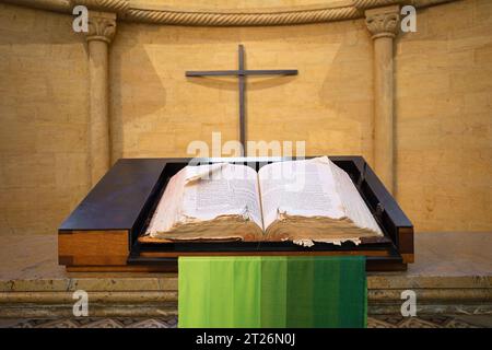 Open Bible on wooden background, Holy book of Christianity. Cross on the wall. Stock Photo