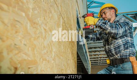 Construction Contractor Worker Installing Plywood Board on the Building Wall Stock Photo