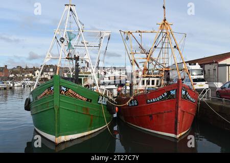 A green boat (Queensberry BA156) and a red boat (Marigold A52) moored in Arbroath Harbour on the east coast of Scotland. Stock Photo