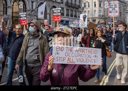 Woman marches through central London on the Free Palestine protest holding a protest banner 'End The Apartheid, Occupation', October 2023. Stock Photo