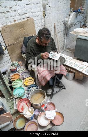 A Mexican craftsman hand paints ceramic plates at Gorky Gonzales pottery workshop in Guanajuato, Mexico. The workshop rescued traditional majolica pottery which had become lost to time. Stock Photo