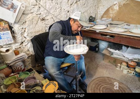 A Mexican craftsman hand paints ceramic plates at Gorky Gonzales pottery workshop in Guanajuato, Mexico. The workshop rescued traditional majolica pottery which had become lost to time. Stock Photo