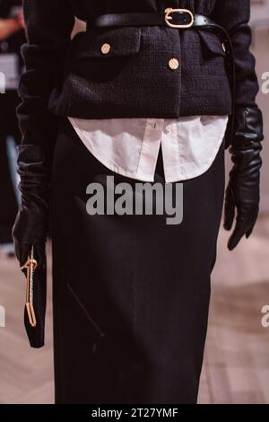 Classic black jacket, leather belt, gloves and classic velvet clutch. Fashion model posing on backstage Stock Photo