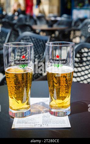 Two half full Heineken badged beer glasses on a table top in a cafe bar in Bordeaux, a port city on the Garonne River in southwestern France Stock Photo
