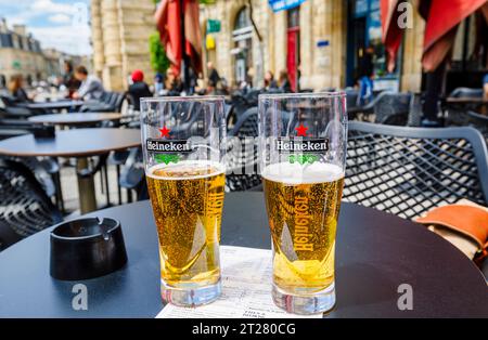Two half full Heineken badged beer glasses on a table top in a cafe bar in Bordeaux, a port city on the Garonne River in southwestern France Stock Photo