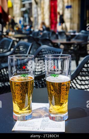 Two half full Heineken badged beer glasses on a table top in a cafe bar in Bordeaux, a port city on the Garonne River in southwestern France Stock Photo