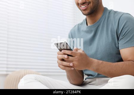Man using modern mobile phone indoors, closeup. Space for text Stock Photo