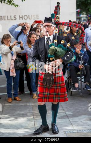 A Scottish bagpiper plays at the Pearly Kings and Queens Harvest Festival at Guildhall Yard, London, England. Stock Photo
