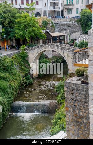 View of the Kriva Cuprija (Crooked Bridge) over the Radobolja River, a small and old stone bridge in Mostar, Bosnia and Herzegovina, built in 1558 by Stock Photo