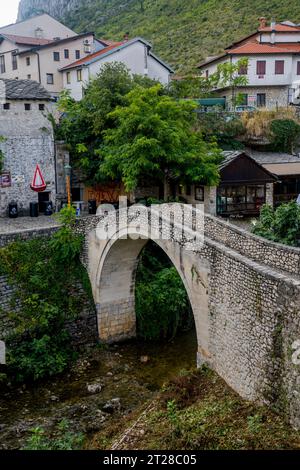 View of the Kriva Cuprija (Crooked Bridge) over the Radobolja River, a small and old stone bridge in Mostar, Bosnia and Herzegovina, built in 1558 by Stock Photo