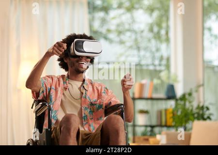 Excited man with disability playing racing videogame in vr headset Stock Photo