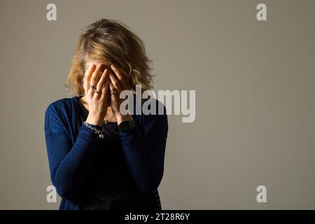 PICTURE POSED BY A MODEL File photo dated 09/03/15 of a woman with her hands covering her face. Women should receive 'menopause checks' at 40, MPs have said as experts have highlighted the risk of women developing heart problems during the menopausal period. Issue date: Wednesday October 18, 2023. Stock Photo