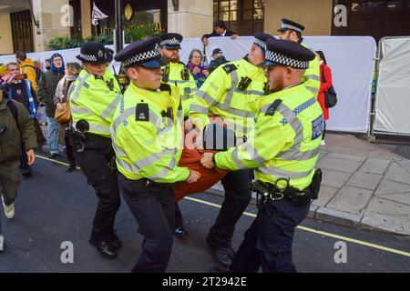 London, UK. 17th October 2023. Police officers arrest a climate protester outside InterContinental Hotel in Park Lane during the Energy Intelligence Forum, a summit of the biggest oil company executives. The protesters blocked the entrance and tried to prevent delegates from entering the hotel. Credit: Vuk Valcic/Alamy Live News Stock Photo