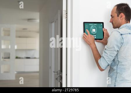 Young electrician installing security alarm on wall Stock Photo
