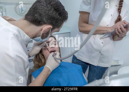A female dentist treats a patient's teeth. The dentist makes a professional cleaning of the teeth of a young female patient in the dental office. Stock Photo