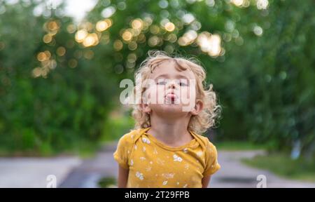 Child sticks out tongue on street portrait. Selective focus. Kid. Stock Photo