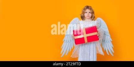 Angel child hold gift present. Angel child. Isolated studio shot. Cute kid with angel wings. Banner for website header design. Stock Photo