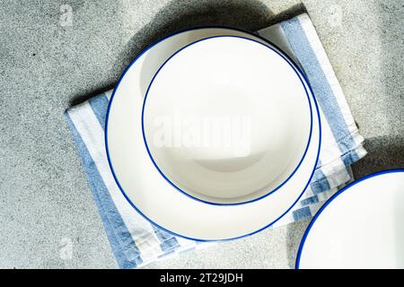 Top view of minimalistic rustic table setting with white plates and striped napkin on gray surface in daylight Stock Photo