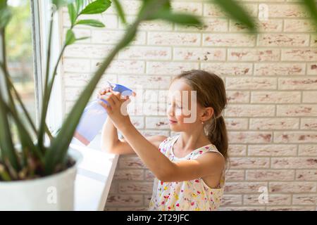 From above of side view of girl in dress spraying water on to the face with your eyes closed at home Stock Photo