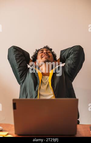 Positive male remote worker using netbook for online project while working on hoffice at table in blurred background Stock Photo