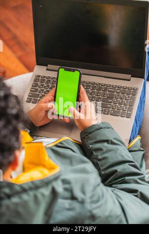High angle of crop anonymous male remote worker using netbook and phone for online project while working on hoffice at table Stock Photo