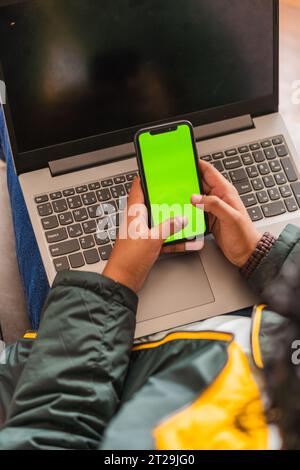 High angle of crop anonymous male remote worker using netbook and phone for online project while working on hoffice at table Stock Photo