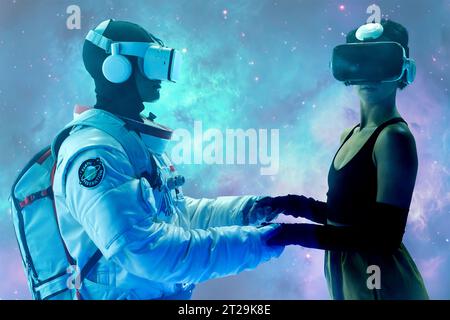 Anonymous male astronaut in spacesuit and woman in casual clothes wearing virtual reality goggles while standing and holding hands Stock Photo