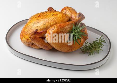 From above of whole Roasted Chicken ready to be served on a concrete plate plate on a white table Stock Photo