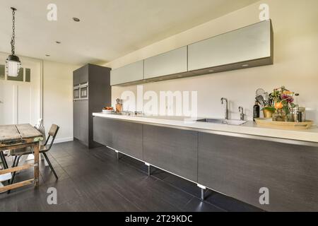 Interior of spacious kitchen with clean long white countertop and gray cabinets in modern apartment Stock Photo