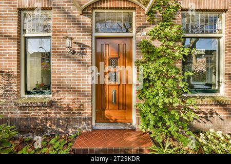 Exterior of brick house with orange front door and green ivy plants growing on wall during daytime Stock Photo