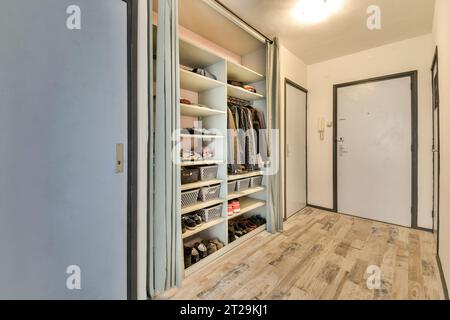 White closet filled with various clothes and shoes on shelves in contemporary apartment with closed doors Stock Photo