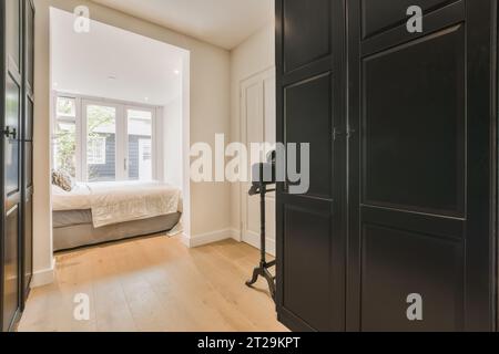 Interior of spacious bedroom with large black wardrobes and comfortable bed next to window at modern apartment Stock Photo