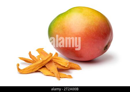 Heap of dried mango chips close up and fresh mango at the background close up isolated on white background Stock Photo