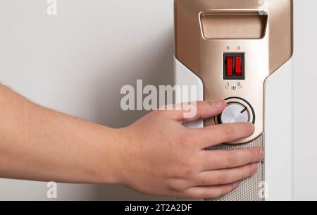 Adjusting the heating power of an electric oil heater on a white background. Heating season is autumn and winter. Stock Photo