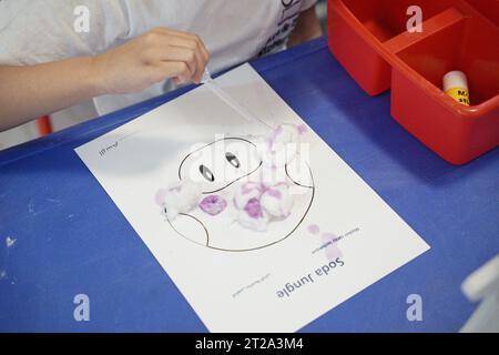 kids Toad arts and crafts, kid donig crafts with cotton and dropping colors. kids doing art and crafts in classroom. Stock Photo