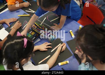 Kids chalk drawing. Kids colouring on black paper using chalk technique. Stock Photo
