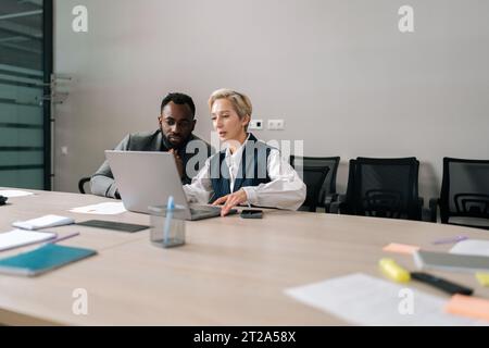 Remote view of female manager insurer consulting black male customer with laptop at meeting. Mature saleswoman or mentor showing online presentation Stock Photo